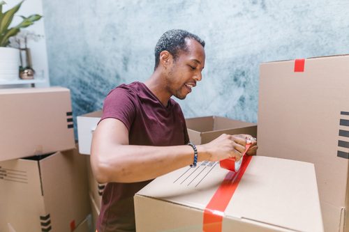 Man amid removal boxes working on laptop